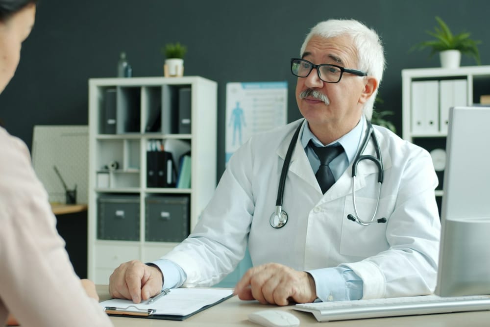 An aviation medical examiner talking through a pilot's medical assessment at a clinic desk An aviation medical examiner talking through a pilot's medical assessment at a clinic desk